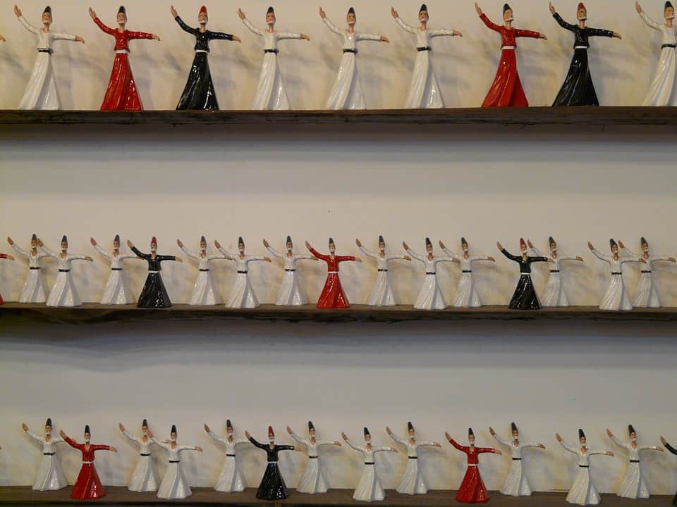 Rows of miniature whirling dervish figurines displayed on wooden shelves